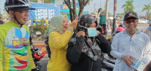Bupati Kobar Hj Nurhidayah memasang masker kepada warga saar CFD di Bundaran Pancasila, Minggu (8/3). Foto : yusbob